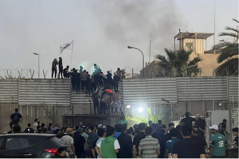 Los manifestantes escalan un muro en la Embajada de Suecia en Bagdad el jueves. (Foto AP/Ali Jabar)