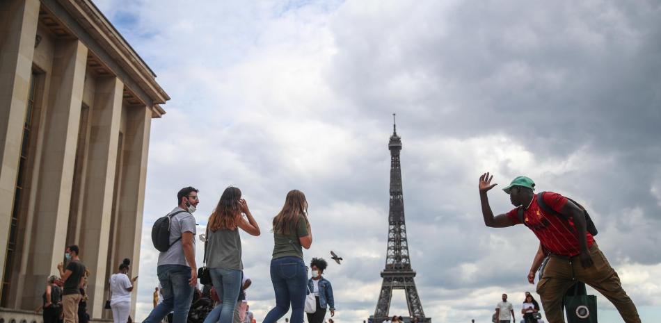 Un vendedor de souvenirs de la Torre Eiffel explica cómo tomarse una foto con la Torre Eiffel a una mujer, en la plaza Trocadero en París, Francia, el 14 de agosto de 2020.MOHAMMED BADRA
