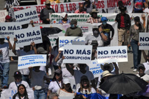 La gente porta carteles que dicen "No más corrupción" durante una protesta contra las políticas del presidente Nayib Bukele y su reelección el Día de la Independencia en San SalvadorAFP