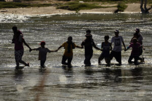 Migrantes forman una cadena humana para cruzar el Río Bravo desde México a Estados Unidos, el 21 de septiembre de 2023, en Eagle Pass, Texas.AP