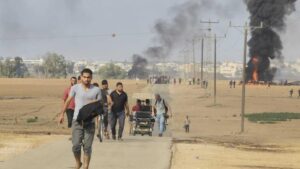 Palestinos se alejan del kibbutz de Kfar Azza, Israel, cerca de la valla fronteriza de la Franja de Gaza, el 7 de octubre de 2023. (AP)