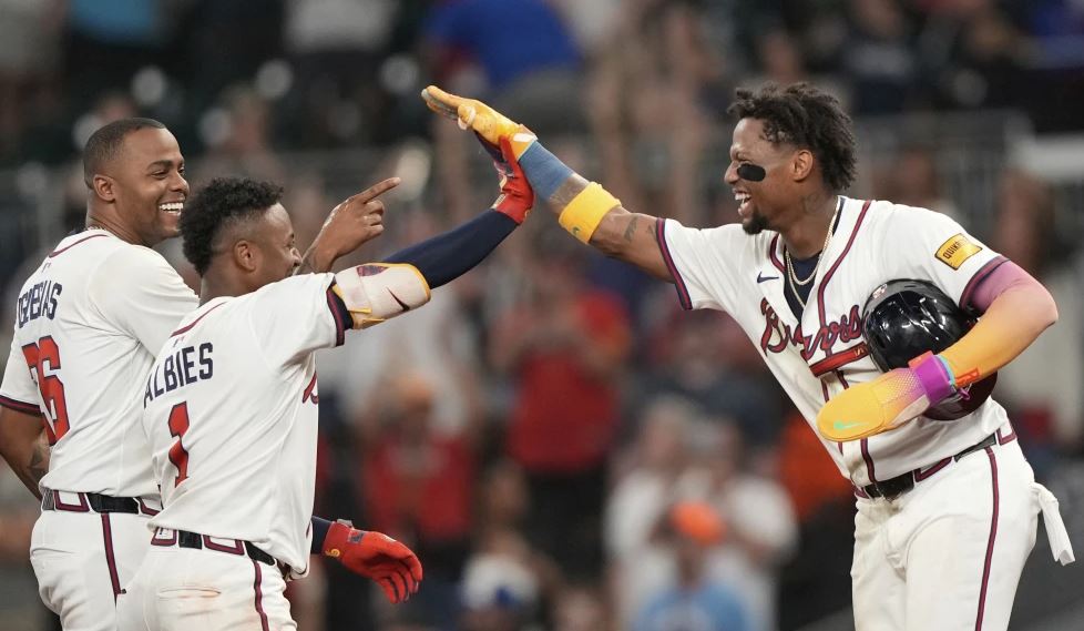 El venezolano Ronald Acuña Jr. (derecha), de los Bravos de Atlanta, festeja junto a Ozzie Albies y el cubano Raisel Iglesias