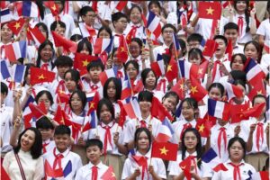 Niños sostienen banderas de Vietnam y Francia en una ceremonia de bienvenida para el presidente de Francia, Emmanuel Macron