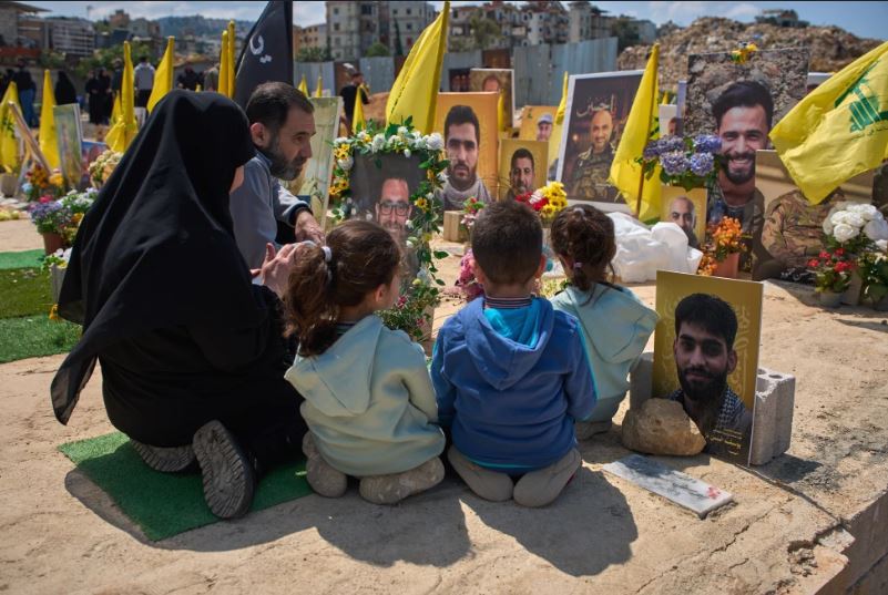 Familiares rezan en la tumba de una persona enterrada junto a combatientes de Hezbollah muertos en ataques israelíes